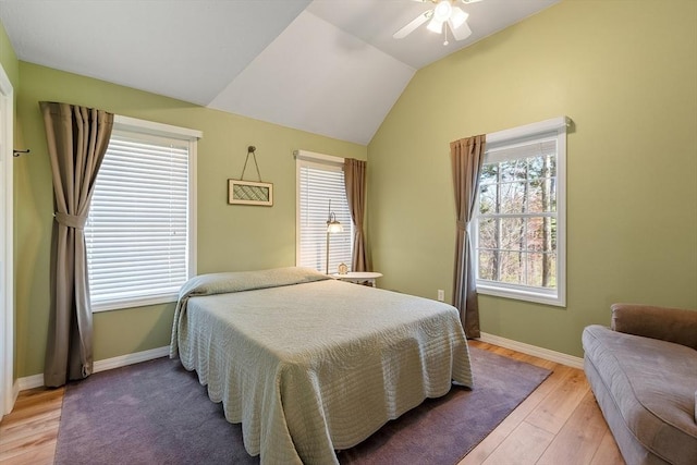 bedroom with a ceiling fan, light wood-style flooring, vaulted ceiling, and baseboards