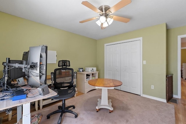 office area with baseboards, visible vents, a ceiling fan, and light wood finished floors