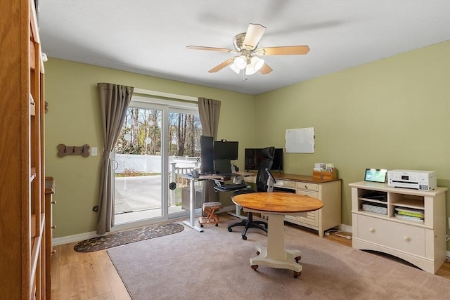 office area with a ceiling fan, baseboards, and light wood-type flooring