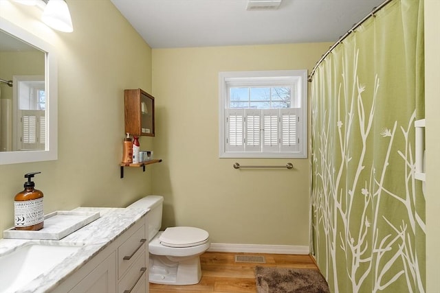 bathroom with wood finished floors, toilet, vanity, baseboards, and visible vents