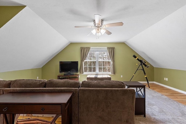 carpeted living area with baseboards, wood finished floors, ceiling fan, and lofted ceiling