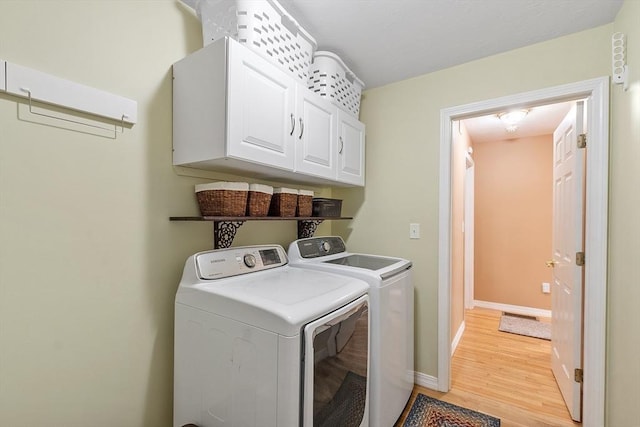 clothes washing area with separate washer and dryer, cabinet space, baseboards, and light wood-style floors