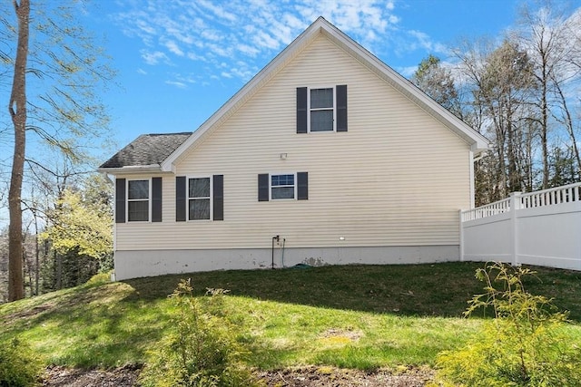 view of side of home featuring a yard and roof with shingles