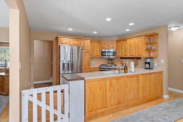kitchen with appliances with stainless steel finishes, baseboards, recessed lighting, light wood finished floors, and a peninsula