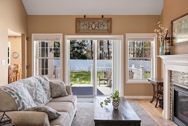 living area with baseboards, wood finished floors, and a tile fireplace