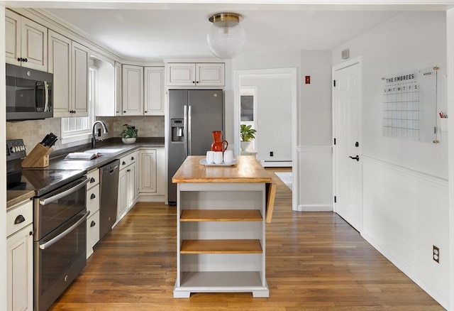 kitchen with a baseboard radiator, sink, dark hardwood / wood-style flooring, decorative backsplash, and stainless steel appliances