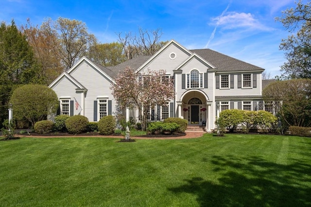 view of front facade with a front lawn and a shingled roof
