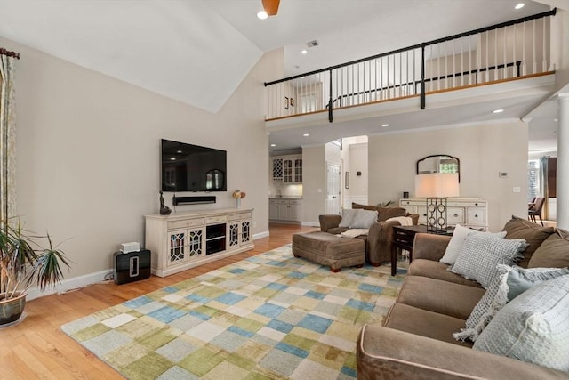 living area with wood finished floors, high vaulted ceiling, and baseboards