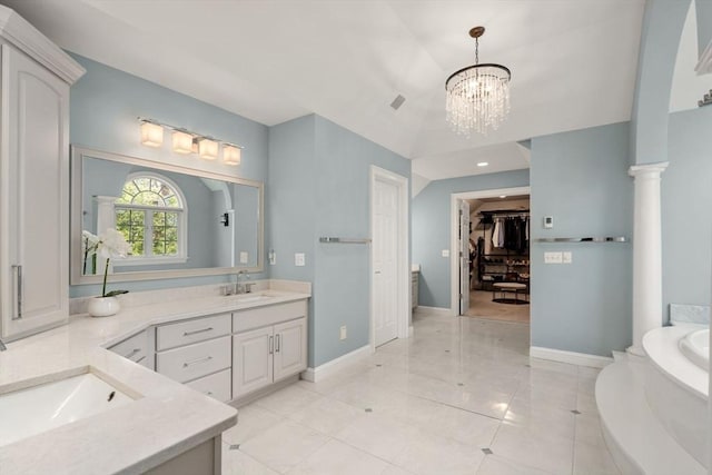 bathroom with vanity, baseboards, a bath, a walk in closet, and a chandelier