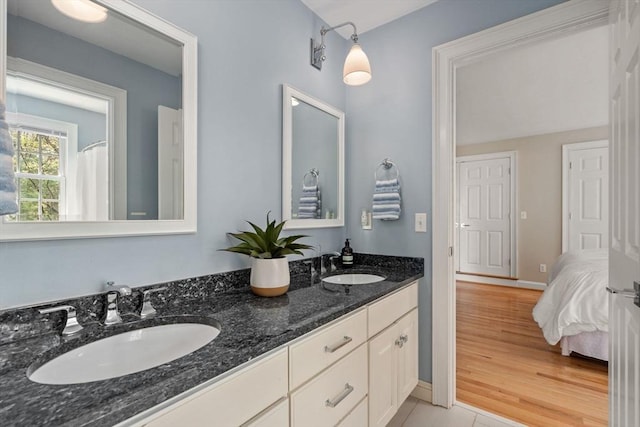 ensuite bathroom featuring double vanity and baseboards