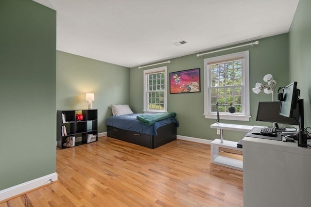 bedroom featuring light wood finished floors, baseboards, and an office area