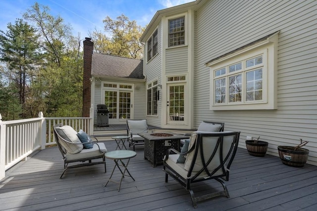 wooden terrace with an outdoor fire pit and grilling area
