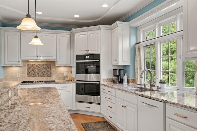 kitchen featuring stainless steel appliances, a sink, white cabinets, pendant lighting, and ornamental molding