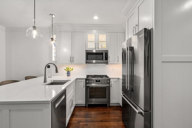 kitchen with crown molding, premium appliances, decorative backsplash, a peninsula, and a sink