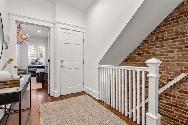 hall with brick wall and wood finished floors