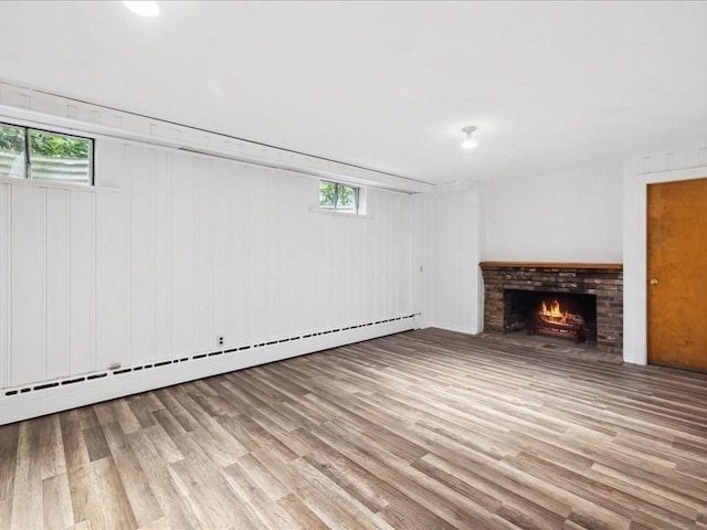 234 Lowell Rd, Wellesley, MA 02481 - below grade area with wood finished floors, plenty of natural light, a baseboard heating unit, and a brick fireplace