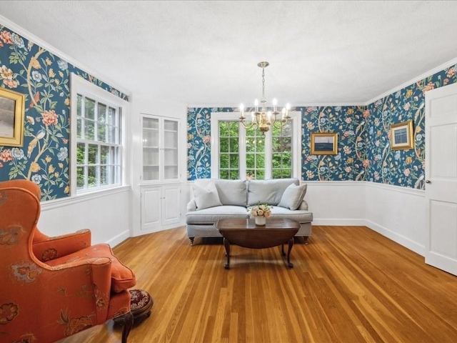 234 Lowell Rd, Wellesley, MA 02481 - living room featuring wallpapered walls, wood finished floors, a wainscoted wall, crown molding, and a chandelier