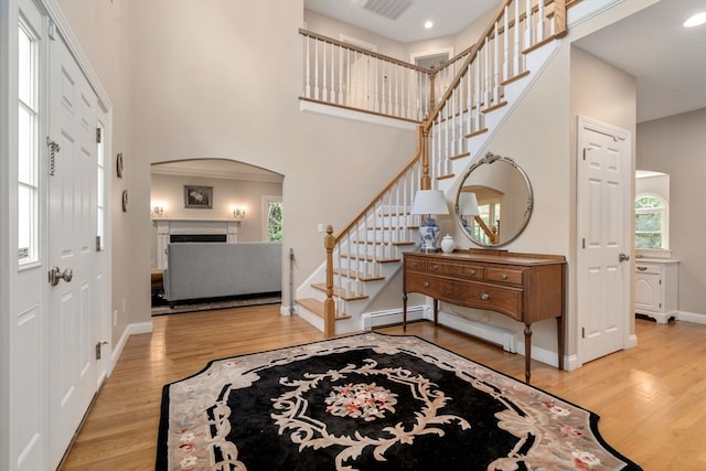 entryway featuring a baseboard radiator, a high ceiling, and light hardwood / wood-style floors