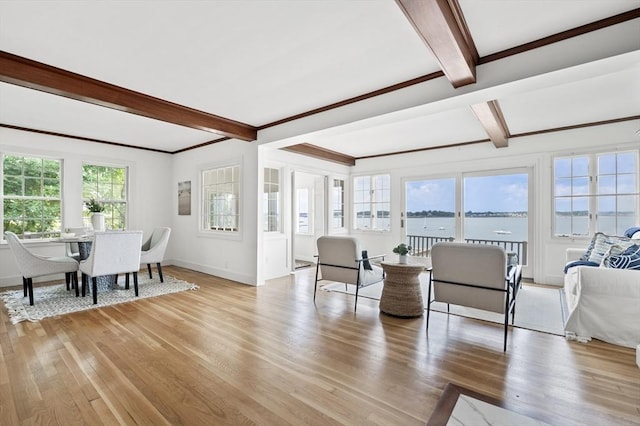 living area with beamed ceiling, baseboards, light wood finished floors, and a water view