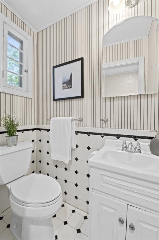 half bath featuring tile patterned flooring, wallpapered walls, toilet, and vanity