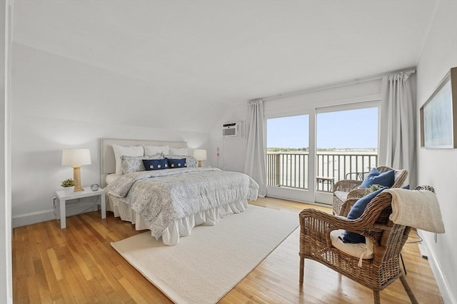 bedroom with lofted ceiling, access to exterior, a water view, light wood-type flooring, and baseboards