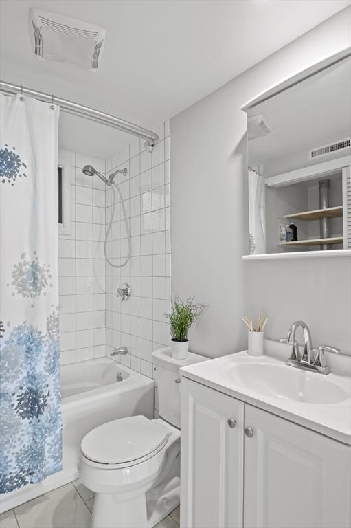 full bathroom with visible vents, toilet, vanity, and shower / bath combo with shower curtain