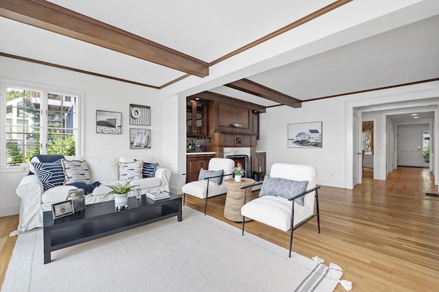 living room with light wood finished floors, beam ceiling, baseboards, and a warm lit fireplace