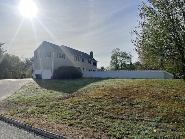 34 Liberty Ln, Ashburnham, MA 01430 - view of side of property with a chimney, an attached garage, fence, and concrete driveway