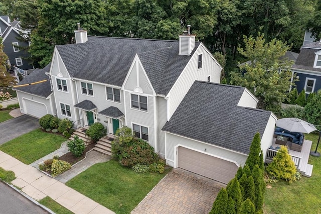 view of front of house with a garage, roof with shingles, decorative driveway, and a chimney