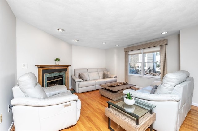 living area with recessed lighting, light wood-style flooring, baseboards, and a high end fireplace