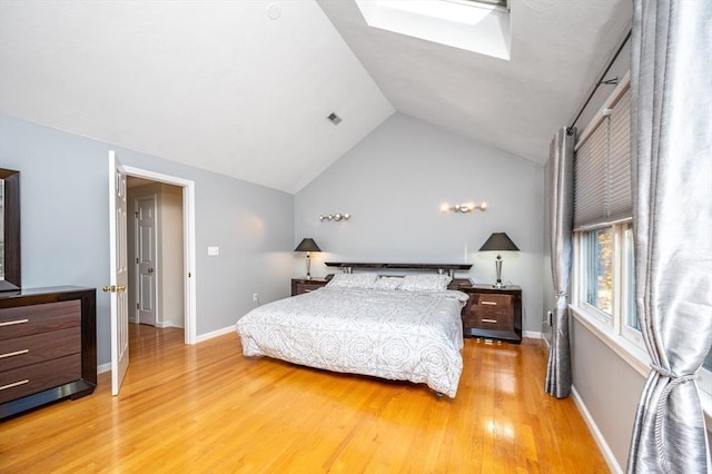 bedroom with light wood-type flooring, vaulted ceiling with skylight, visible vents, and baseboards