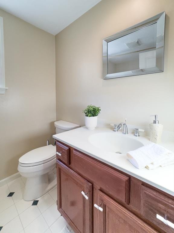 half bathroom with toilet, tile patterned flooring, and vanity