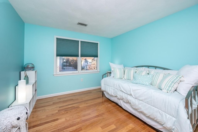 bedroom featuring light wood-type flooring, visible vents, and baseboards