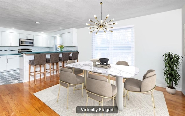 dining space featuring recessed lighting, a textured ceiling, light wood finished floors, and an inviting chandelier