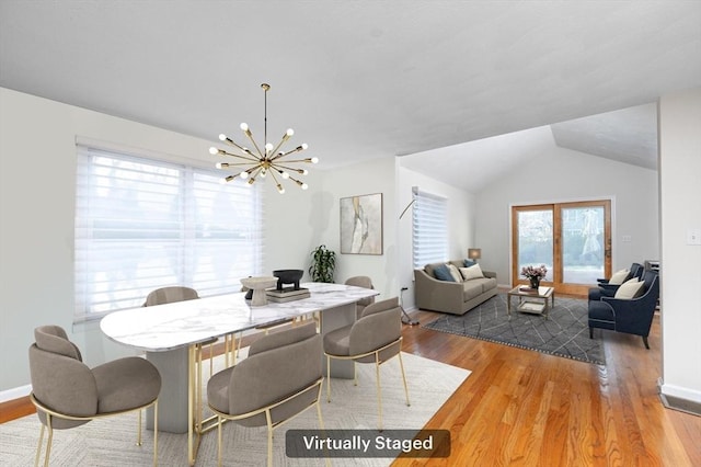 dining space with a notable chandelier, baseboards, vaulted ceiling, and wood finished floors