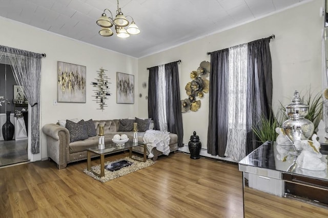 living area with crown molding, a chandelier, and wood finished floors
