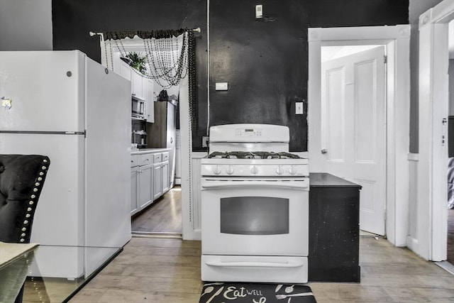 kitchen with white appliances, light wood-style flooring, and white cabinetry