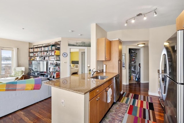 kitchen with dark wood finished floors, stainless steel appliances, light stone counters, and a sink