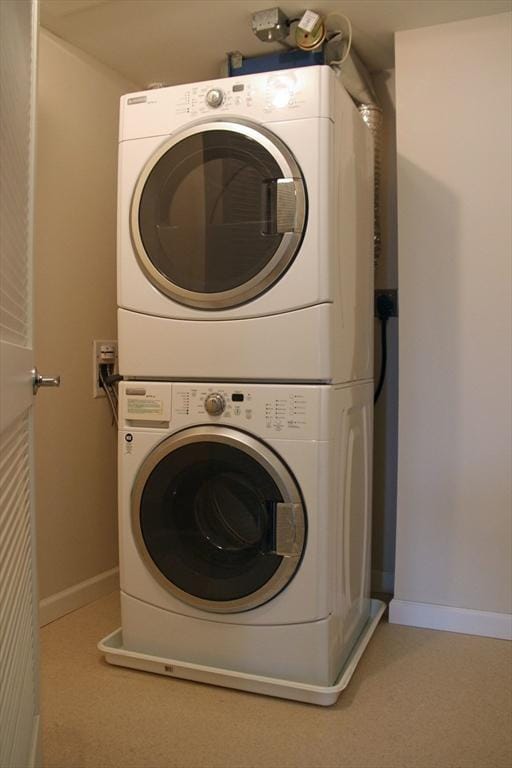 laundry area with laundry area, stacked washer and dryer, and baseboards