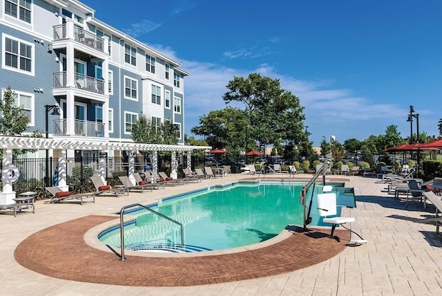 community pool with a patio area and fence