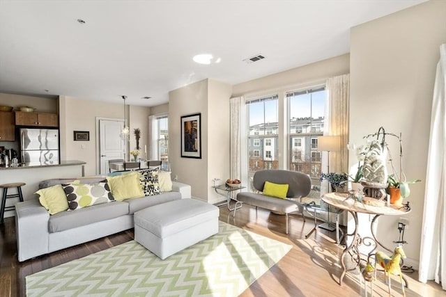 living room with wood finished floors, visible vents, and baseboards