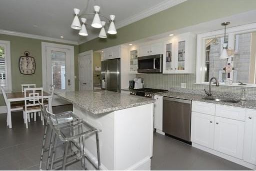 kitchen featuring pendant lighting, appliances with stainless steel finishes, backsplash, a notable chandelier, and white cabinetry