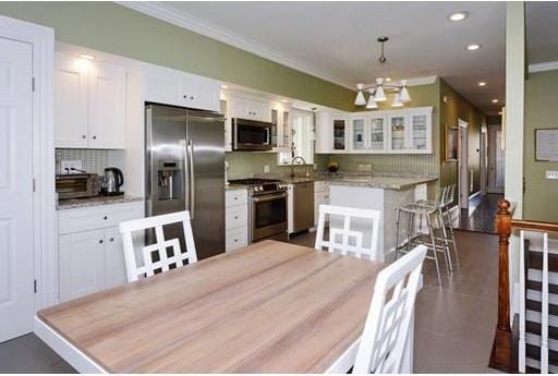 kitchen featuring backsplash, stainless steel appliances, a notable chandelier, and white cabinets