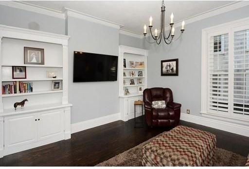 living area featuring an inviting chandelier, ornamental molding, and dark hardwood / wood-style floors