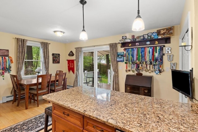kitchen with brown cabinets, light wood finished floors, healthy amount of natural light, and light stone countertops