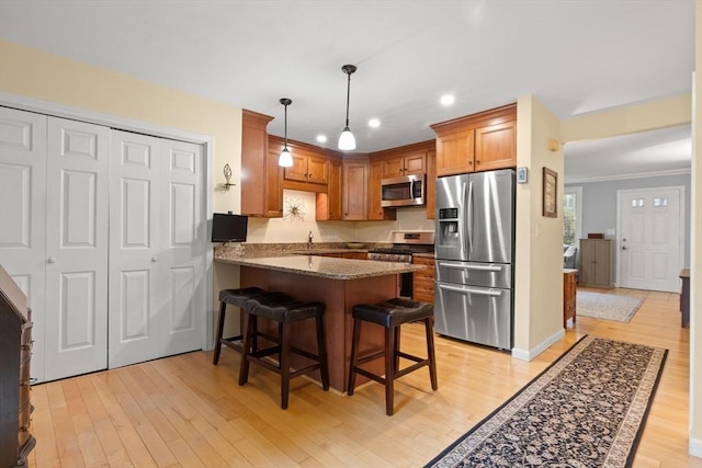 kitchen featuring stainless steel appliances, a peninsula, recessed lighting, light wood-type flooring, and a kitchen breakfast bar