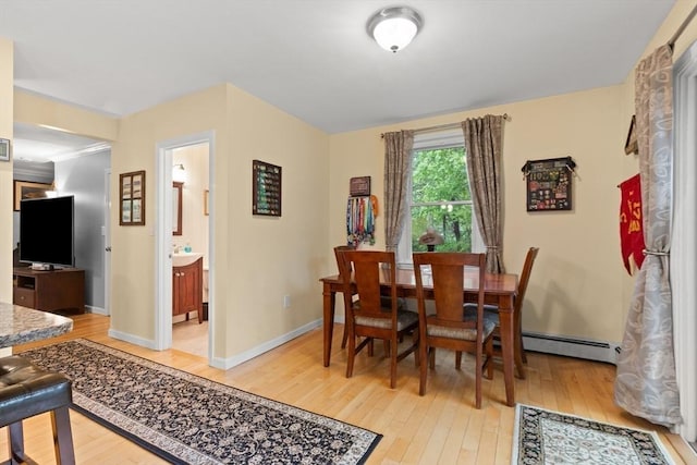 dining space featuring a baseboard heating unit, light wood-style floors, and baseboards