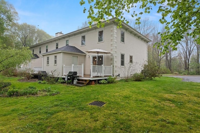 back of property featuring a deck, a yard, and a chimney