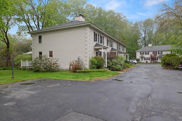 view of side of property featuring a chimney, driveway, and a yard
