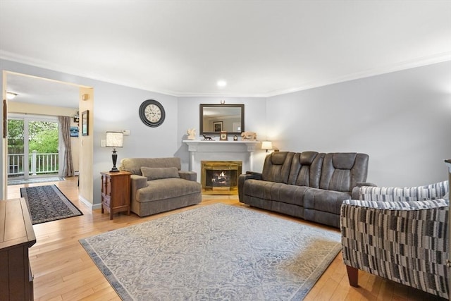living room featuring light wood-type flooring, crown molding, a lit fireplace, recessed lighting, and baseboards